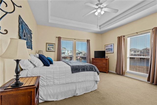 bedroom with ceiling fan, a raised ceiling, and light colored carpet