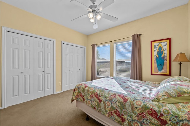 carpeted bedroom with ceiling fan and two closets