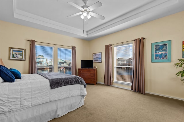 carpeted bedroom with ceiling fan and a raised ceiling