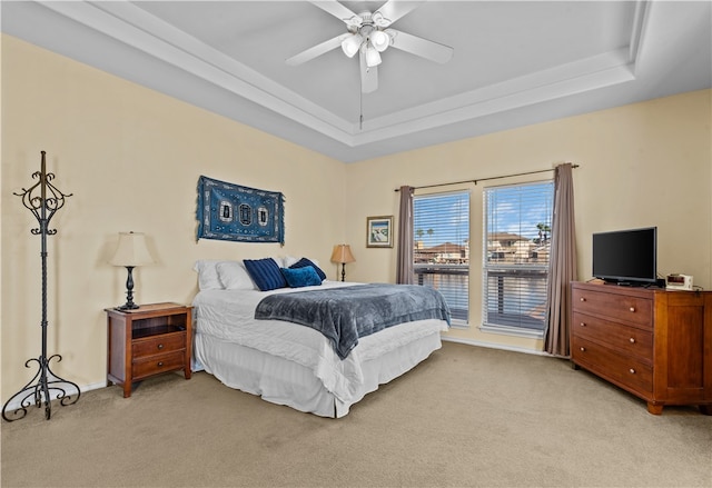 bedroom featuring light carpet, ceiling fan, and a tray ceiling