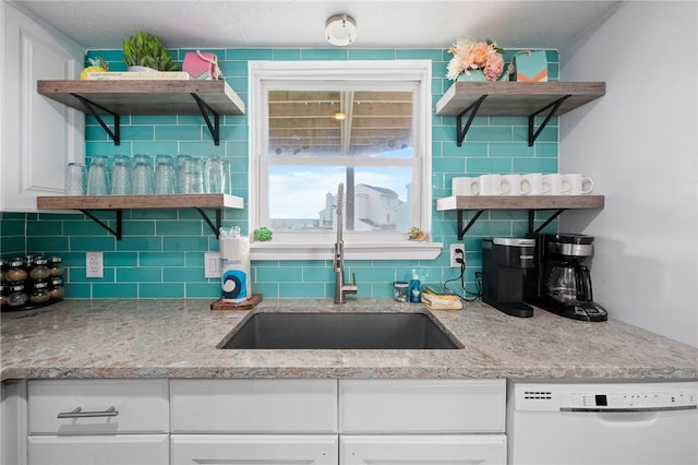 kitchen with white dishwasher, white cabinetry, sink, and decorative backsplash