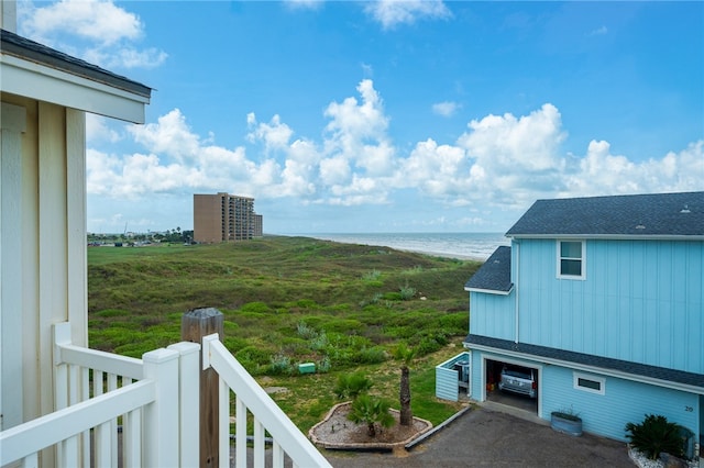 view of yard featuring a garage, a water view, and a beach view