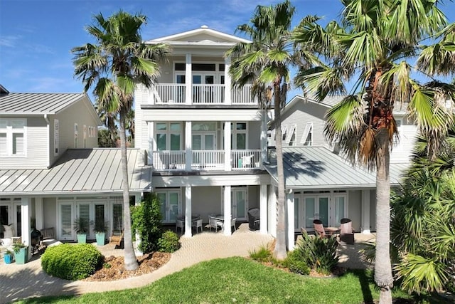 rear view of house featuring french doors, a yard, a balcony, and a patio