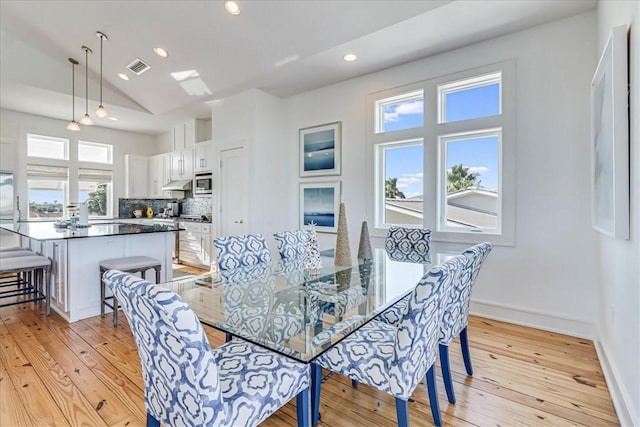 dining room featuring lofted ceiling, light hardwood / wood-style flooring, and plenty of natural light