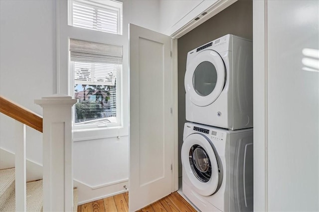 washroom featuring stacked washer and clothes dryer and light hardwood / wood-style floors