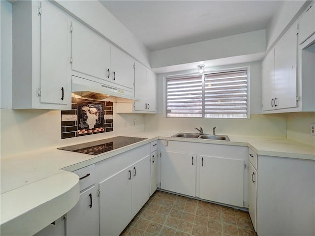 kitchen featuring black electric stovetop, backsplash, sink, and white cabinets