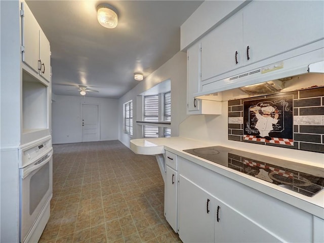 kitchen featuring ceiling fan, white oven, backsplash, black electric stovetop, and white cabinets