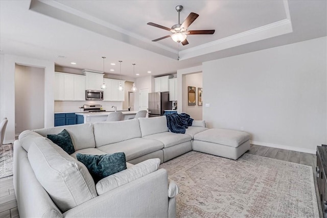 living room with ornamental molding, a raised ceiling, and ceiling fan