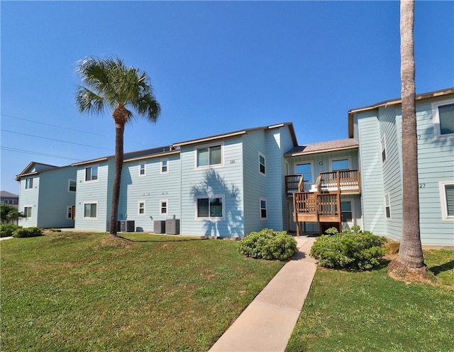 rear view of property featuring a deck, a lawn, and cooling unit