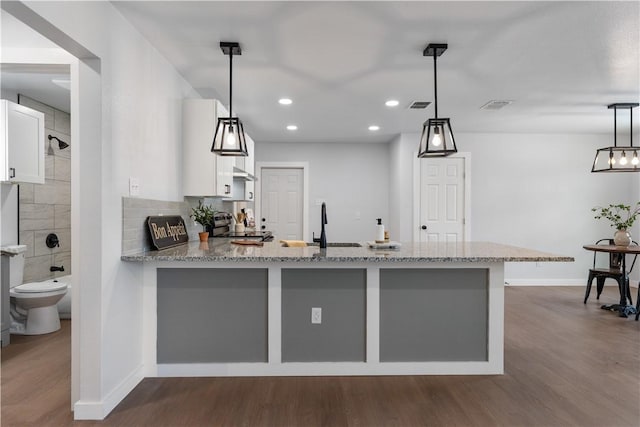 2809 Tarlton St, Corpus Christi, TX 78405 - kitchen featuring dark wood-type flooring, light stone countertops, white cabinetry, a peninsula, and recessed lighting