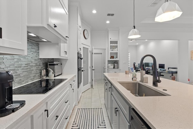 kitchen featuring white cabinetry, sink, light stone counters, pendant lighting, and black electric stovetop