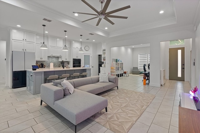 living room featuring sink, ceiling fan, light tile patterned floors, a tray ceiling, and crown molding