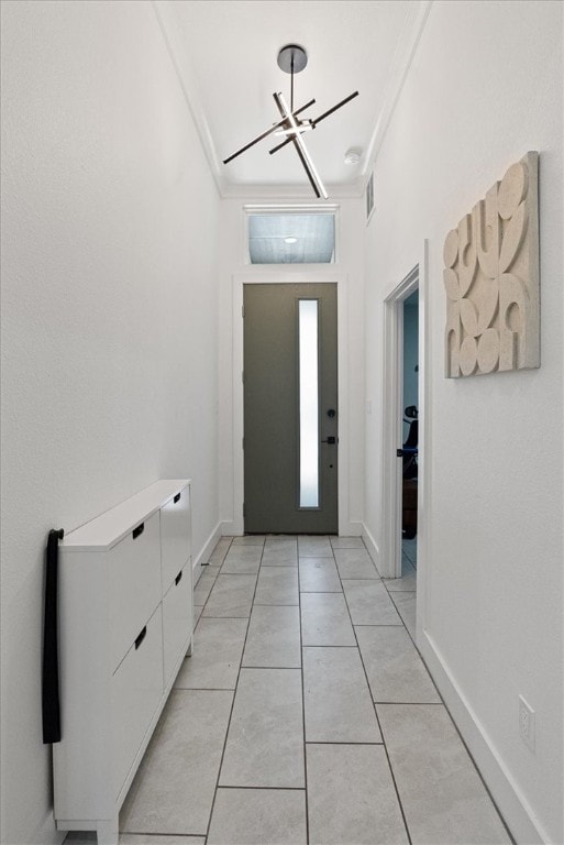 tiled entryway featuring a notable chandelier and ornamental molding