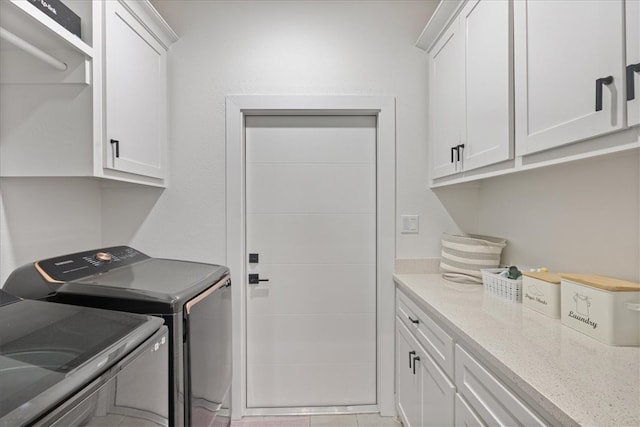 washroom with separate washer and dryer, cabinets, and light tile patterned floors