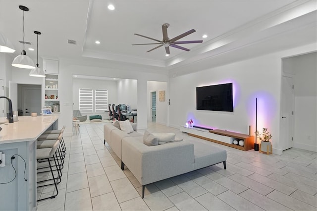 living room featuring crown molding, ceiling fan, and a raised ceiling