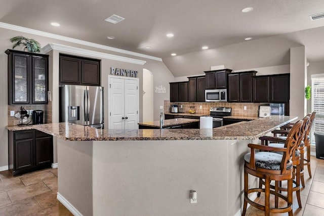 kitchen with a large island, appliances with stainless steel finishes, and vaulted ceiling