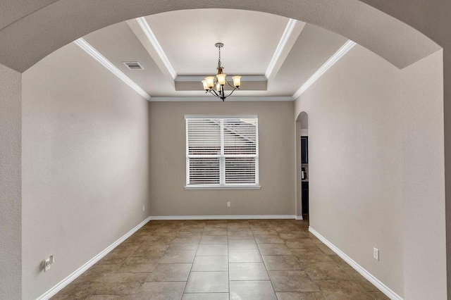 empty room featuring a raised ceiling, a chandelier, and ornamental molding