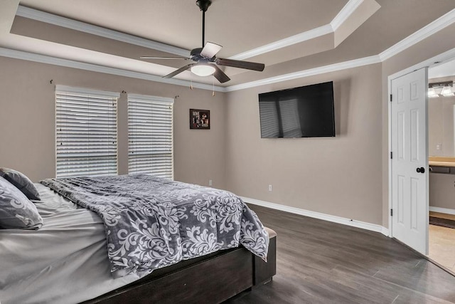 bedroom featuring dark hardwood / wood-style flooring, a tray ceiling, ceiling fan, crown molding, and connected bathroom