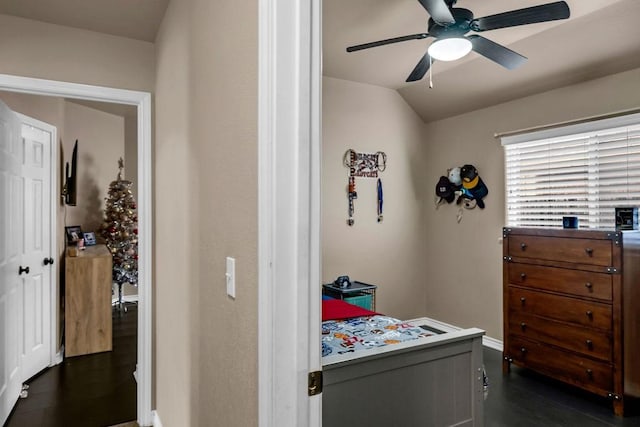 bedroom with dark hardwood / wood-style flooring, vaulted ceiling, and ceiling fan