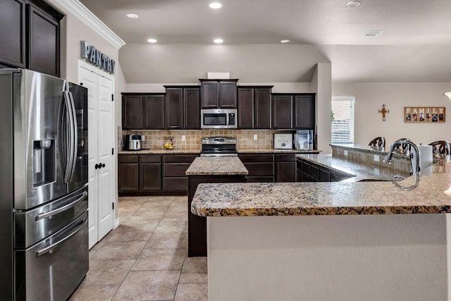 kitchen with backsplash, a center island with sink, crown molding, sink, and stainless steel appliances