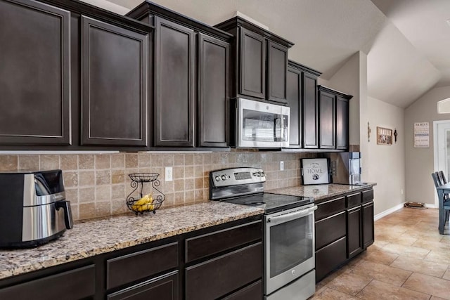 kitchen with light stone countertops, backsplash, dark brown cabinetry, stainless steel appliances, and lofted ceiling