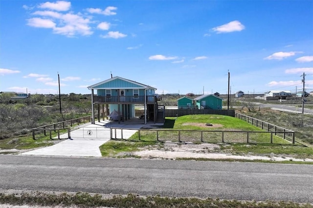 view of front facade with stairway, fence, a carport, concrete driveway, and a front lawn