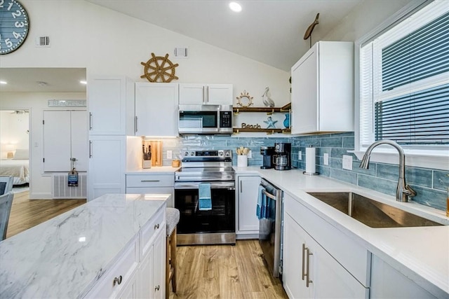 kitchen featuring visible vents, a sink, lofted ceiling, appliances with stainless steel finishes, and open shelves