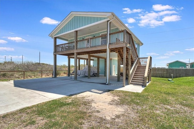 rear view of house with board and batten siding, fence, stairway, a lawn, and driveway