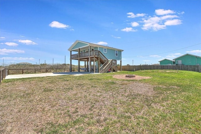 back of property featuring stairs, a yard, a fenced backyard, and an outdoor fire pit