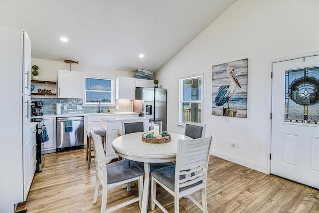 dining area with light wood finished floors, recessed lighting, baseboards, and lofted ceiling