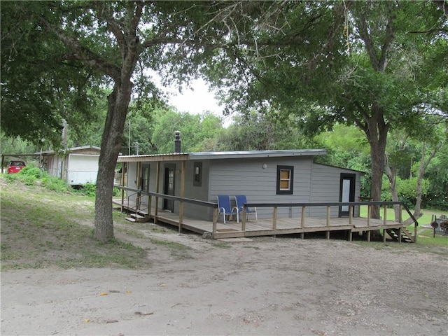 119 Horse Shoe Clf, Sandia, TX 78383 - view of front of home featuring a deck, view of wooded area, and a chimney