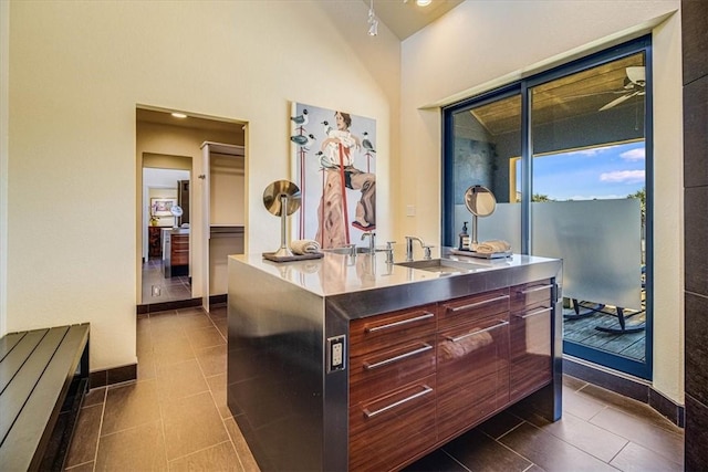 kitchen with dark tile patterned flooring, stainless steel countertops, a sink, baseboards, and modern cabinets