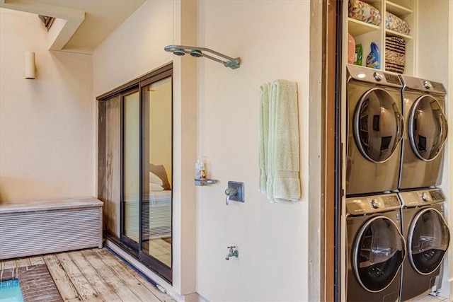 clothes washing area featuring stacked washer and clothes dryer, light wood finished floors, and laundry area