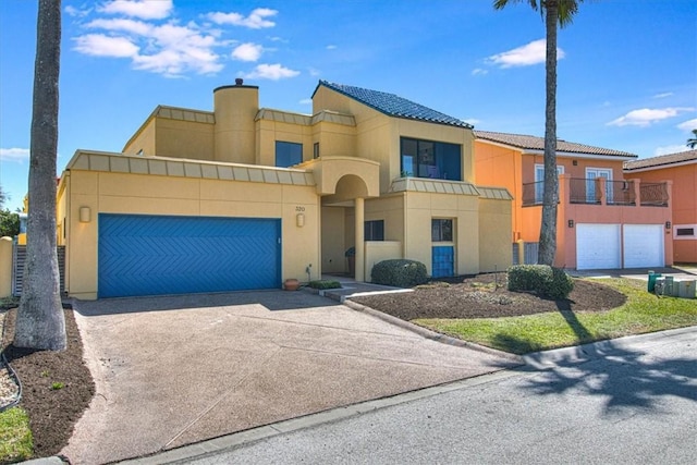 view of front of home with a garage, a tile roof, driveway, and stucco siding