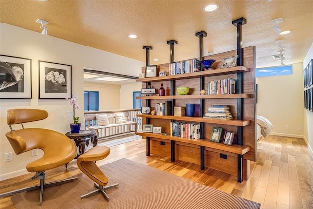 living area featuring recessed lighting, baseboards, a textured ceiling, and light wood finished floors