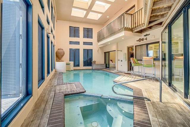 view of pool featuring a skylight and a pool with connected hot tub