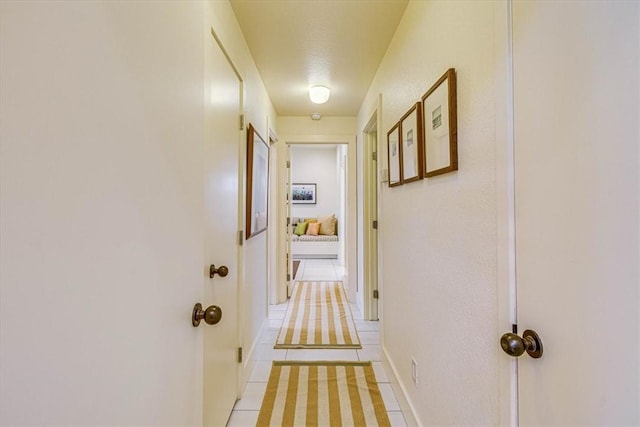 hallway with light tile patterned flooring and baseboards