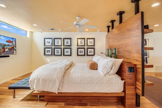 bedroom with a textured ceiling, wood finished floors, visible vents, and recessed lighting