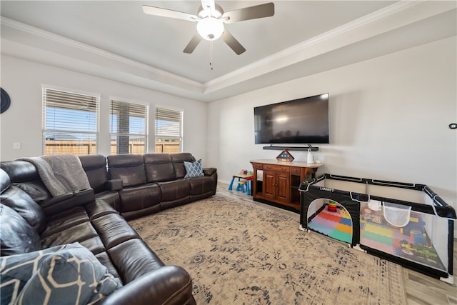 living room featuring a tray ceiling, ornamental molding, ceiling fan, and hardwood / wood-style flooring