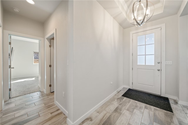 doorway featuring a raised ceiling and a chandelier