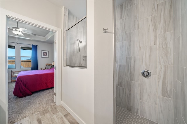 bathroom featuring crown molding, ceiling fan, hardwood / wood-style floors, a tile shower, and a tray ceiling