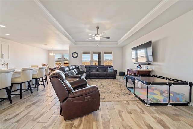 living room featuring sink, crown molding, light wood-type flooring, a raised ceiling, and ceiling fan with notable chandelier