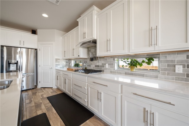 kitchen featuring backsplash, appliances with stainless steel finishes, light stone countertops, and white cabinets