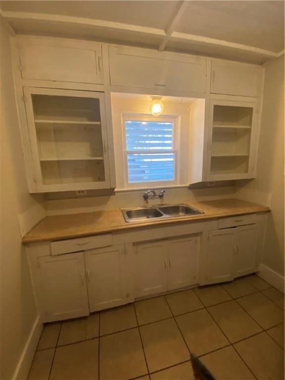 kitchen with light tile patterned flooring, sink, and white cabinets