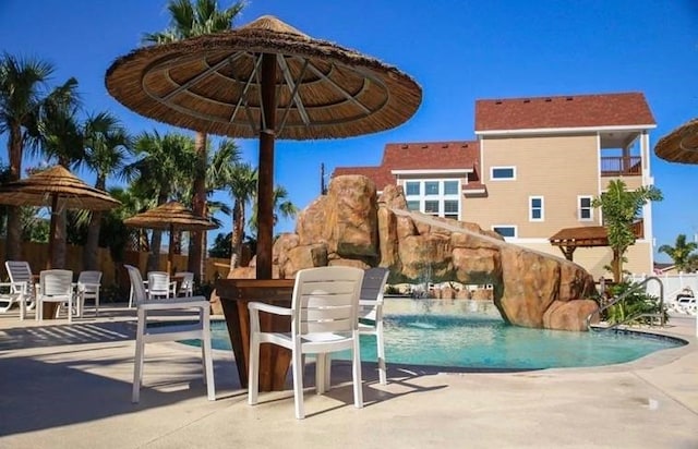 view of swimming pool featuring a water slide, pool water feature, and a patio