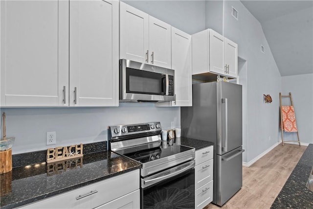 kitchen with stainless steel appliances, dark stone countertops, visible vents, light wood finished floors, and white cabinetry