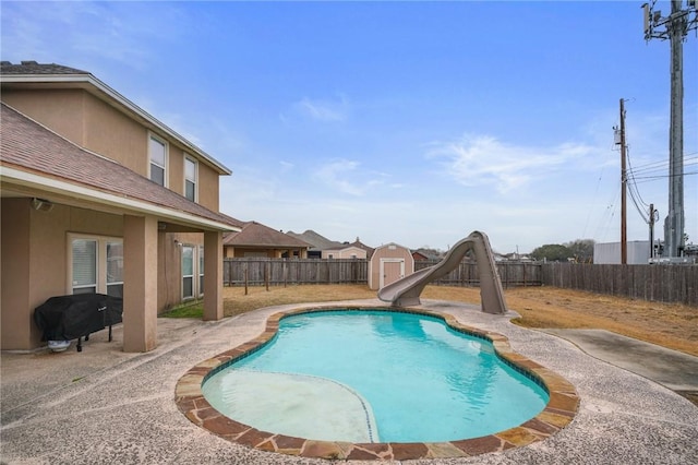 view of swimming pool featuring a storage shed, grilling area, a patio, and a water slide