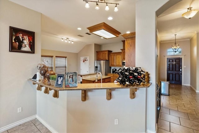 2618 Gentle Wind Ave, Corpus Christi, TX 78414 - kitchen with appliances with stainless steel finishes, brown cabinets, a peninsula, a kitchen breakfast bar, and lofted ceiling