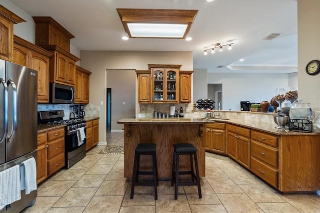2618 Gentle Wind Ave, Corpus Christi, TX 78414 - kitchen with appliances with stainless steel finishes, backsplash, a center island, and a breakfast bar area