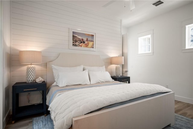 bedroom with wood finished floors, visible vents, and baseboards